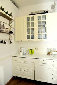 une cuisine avec des armoires et des comptoirs blancs dans l'établissement B&B Il Bijou, à Casalmaggiore