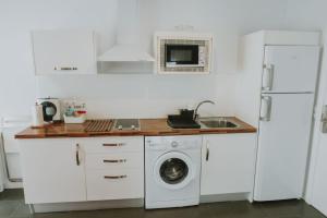 a white kitchen with a washing machine and a sink at Apartamentos ZHR 2 in Zahara de los Atunes