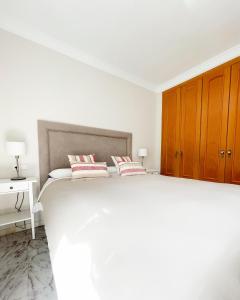 a white bedroom with a large bed with two pillows at Holidays2Malaga Tomas de Echeverria 150 mts to Beach & High Speed wifi & Parking in Málaga