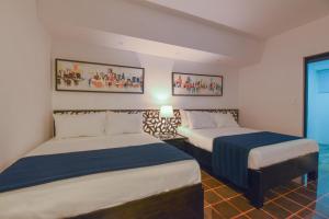 una habitación de hotel con 2 camas y una lámpara en PH 19 Guesthouse Hotel in Gazcue, en Santo Domingo