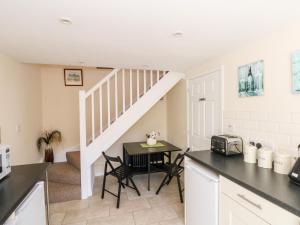 a kitchen with a table and a staircase at Blackbird Cottage in Telford