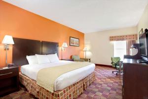 a hotel room with a bed and a television at Days Inn & Suites by Wyndham Ridgeland in Ridgeland