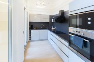 a kitchen with white cabinets and black appliances at JARDIN DES MUSES - 2 PIECES - PARKING Carré d'or Menton in Menton