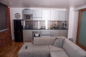 a living room with a couch and a kitchen at Neptune Apartments in Leeds