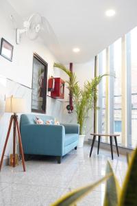 a blue couch in a living room with windows at Gallivanto Inn in New Delhi