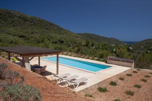a swimming pool with a table and chairs next to a mountain at Hacienda Ses Caletes in Cala San Vicente