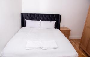 a bedroom with a white bed with a black headboard at Neptune Apartments in Leeds