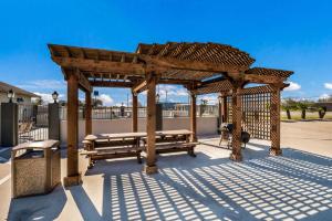 a wooden gazebo with benches in a park at SureStay Hotel by Best Western Alice in Alice