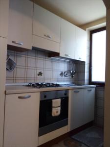 La cuisine est équipée de placards blancs et d'un four avec plaques de cuisson. dans l'établissement Appartamento Graziella, à Mollia