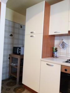 - une cuisine avec des placards blancs et un évier dans l'établissement Appartamento Graziella, à Mollia