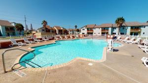 a large swimming pool with lounge chairs in a resort at AH-F120 Newly Remodeled Bottom Floor Condo, Shared PoolHot Tub, Near Marina & Ferry in Port Aransas