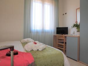 a bedroom with a bed and a desk and a television at Locanda Lighea Rooms in San Vito lo Capo