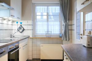 a white kitchen with a sink and a window at Muschelsucher 1 in Nordstrand