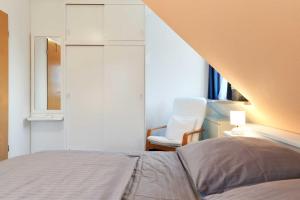 a bedroom with a bed and a chair and a window at Muschelsucher 1 in Nordstrand +30 photos