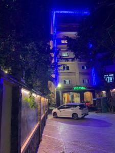 een witte auto geparkeerd naast een gebouw 's nachts bij Ha Long Hotel Thủ Đức HCMC in Ho Chi Minh-stad