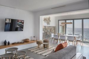 una sala de estar con un sofá, una mesa y sillas en Villa Aether - Infinity Pool Villa Mykonos, en Mykonos ciudad