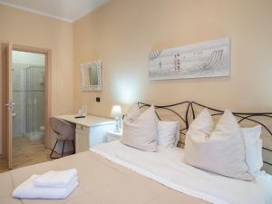 1 dormitorio con cama con almohadas blancas y escritorio en Affittacamere Lunamar en La Spezia
