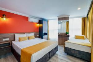 two beds in a hotel room with red walls at Terra Rossa in Antalya