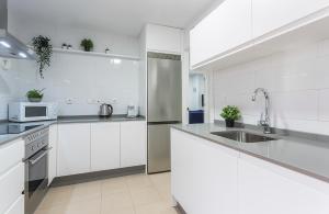a kitchen with white cabinets and a stainless steel refrigerator at Centro 4 Rooms 3 baños Parking in Jerez de la Frontera