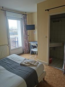 a bedroom with a bed and a window and a chair at le relais de l aiguillon in Châtellerault