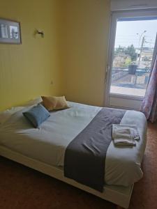 a bed in a room with a large window at le relais de l aiguillon in Châtellerault