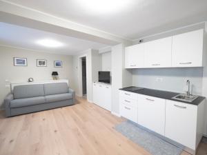 a kitchen with white cabinets and a gray couch at Bellano Holidays - Casa Ortensia in Bellano