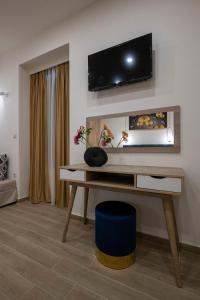 a living room with a desk with a tv on the wall at Kalypso Apartments in Kalamata
