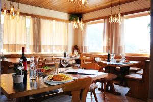 un ristorante con tavoli e sedie in legno e bottiglie di vino di Hotel Sfazù a Poschiavo