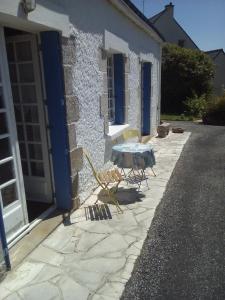 une terrasse avec une table et des chaises devant un bâtiment dans l'établissement La Maison bleu, à Saint-Tugdual