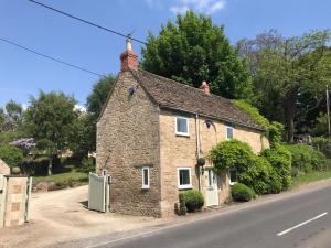 ein altes Steinhaus am Straßenrand in der Unterkunft Turnpike Cottage in Tetbury