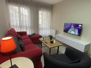 een woonkamer met een rode bank en een tv bij Azcona - 6004 in Noja