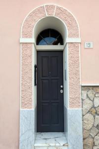 eine schwarze Tür in einem Torbogen in einem rosa Gebäude in der Unterkunft CASA ANTICA in Gaeta