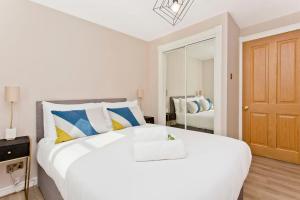 1 dormitorio con 1 cama blanca grande y espejo en Newly Reno'd 2 Bed with Free Parking, en Edimburgo