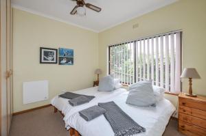 two beds in a room with a large window at Cosy House in Yzerfontein