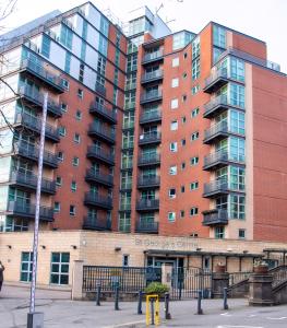 a tall red building with a apartment complex at Mercury Apartments in Leeds