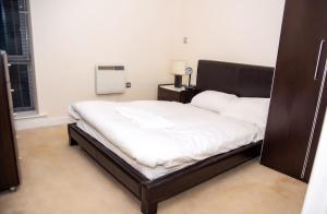 a bedroom with a large bed with white sheets at Mercury Apartments in Leeds