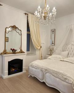 a white bedroom with a fireplace and a chandelier at FSF Boutique Apartament in Timişoara