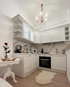 a white kitchen with white cabinets and a chandelier at FSF Boutique Apartament in Timişoara