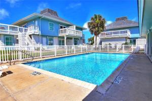 a house with a swimming pool in front of a house at EC116 Newly Remodeled, 2 Story, Three Bedroom Condo, Shared Pool, Boardwalk in Port Aransas