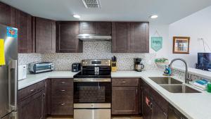 a kitchen with wooden cabinets and a stove top oven at EC116 Newly Remodeled, 2 Story, Three Bedroom Condo, Shared Pool, Boardwalk in Port Aransas