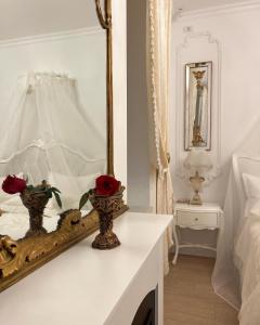 a white bedroom with a mirror and roses on a table at FSF Boutique Apartament in Timişoara