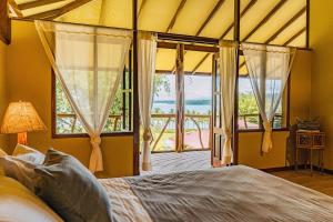 a bedroom with a bed and a large window at Kunken Boutique Hotel & Spa in Puerto Jiménez