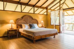 a bedroom with a large bed and two lamps on tables at Kunken Boutique Hotel in Puerto Jiménez