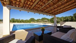 un patio con una piscina con sillas y una mesa en Es Garrover, en Santanyí