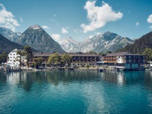 a resort on the water with mountains in the background at aja Fürstenhaus am Achensee in Pertisau