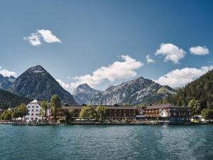 um resort num lago com montanhas ao fundo em Travel Charme Fürstenhaus am Achensee em Pertisau