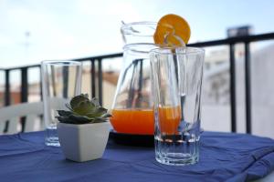 a table with two glasses and a vase with an orange juice at Hostal Can Gil in Pineda de Mar
