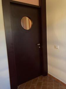 Una puerta negra con una ventana redonda. en Appartamento al 1° piano, zona centrale, en Fonteblanda