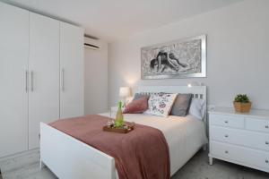 a white bedroom with a bed and a dresser at Apartamento El Jable in Arrecife