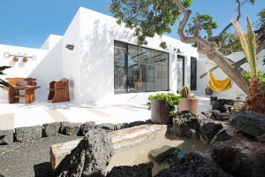 ein weißes Haus mit schwarzen Fenstern und Felsen in der Unterkunft Apartamento El Jable in Arrecife